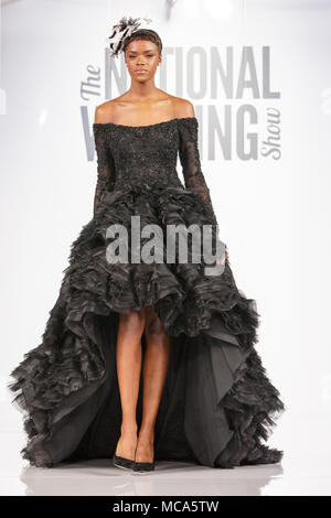 ExCel London, Londres, 14 avril 2018. Une robe noire illustré par un modèle sur le podium. Le mariage National spectacle a lieu au centre des expositions ExCel London ce week-end, mettant en valeur les dernières tendances, suite nuptiale, robes et accessoires tout autour de la planification du mariage parfait. Credit : Imageplotter News et Sports/Alamy Live News Banque D'Images