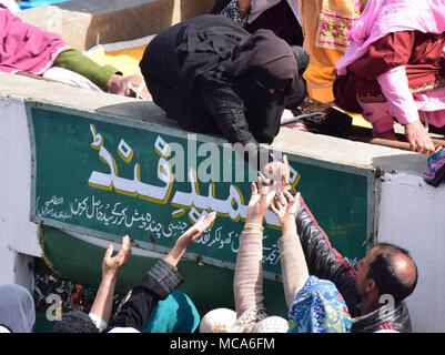 14 avril 2018 - Srinagar, Jammu & Kashmir, Inde - une femme Cachemire distribuant les toffees (considéré comme relique) à l'extérieur de l'Hazratbal Shrine à Srinagar, capitale d'été du Cachemire indien, à l'occasion du Mehraj-ul-Nabi.Chaque année, des milliers de fidèles musulmans de partout au Cachemire rassemble au sanctuaire dans le centre de Srinagar Hazratbal capitale d'été du Cachemire indien pour les prières et pour regarder la sainte relique (me-e-moqadas) qu'on croit être un cheveux de la barbe du prophète Mohammed SAW, affiche pour public sur Meraj-ul Alam et d'autres festivals. Mehraj-ul-Alam, un festival qui marque l'ascension de Prop Banque D'Images