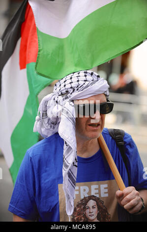 Londres, Royaume-Uni 14 avril 2018 portant un keffieh et tenant un drapeau palestinien lors d'une démonstration en face de l'homme palestinien l'ambassade israélienne à Kensington, Londres, Royaume-Uni. La manifestation était légèrement rauque assez bien pris en charge avec environ 60 personnes présentes. Il a été appelé à protester contre la persistance de la tension dans la bande de Gaza, à la suite des récentes violences entre les deux parties. Londres, Royaume-Uni 14 avril 2018 rassemblement de cinq manifestants pro-Israël chahute la démonstration de l'autre côté de la route. Crédit : Michael Preston/Alamy Live News Banque D'Images