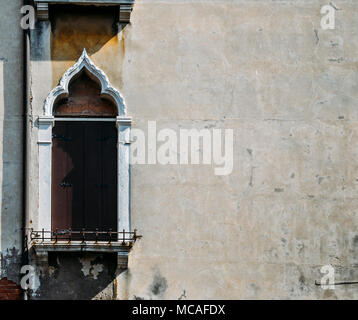 À la recherche jusqu'à un vieux châssis de fenêtre en stuc baigné de lumière, avec des cadres de fenêtre blanche à Venise, Italie. Banque D'Images