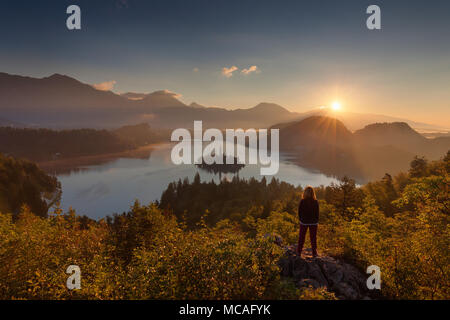 Lone woman standing on vue et regardant le soleil levant au-dessus du lac de Bled, en Slovénie. Concept de vie. Banque D'Images