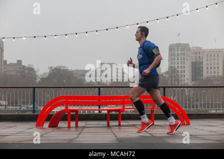 Un homme court le long de la rive sud en face de Jeppe Hein un banc orange -partie de la modification du projet et un banc Social chaîne de lumières sur un jour gris Banque D'Images