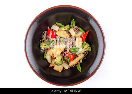 Nouilles de sarrasin avec du poulet et l'ananas dans la sauce teriyaki, isolé sur fond blanc. Nouilles de sarrasin dans une plaque noire. Assiette de rare Banque D'Images