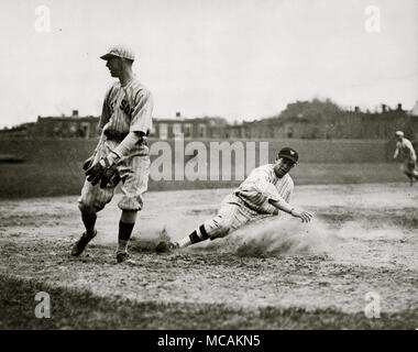 Bucky Harris des Sénateurs à Washington, coulissante comme il vole avec succès la troisième base dans la 7e manche d'un match contre les Red Sox de Boston ; troisième but Joe Dugan watches la balle rouler vers le champ gauche après un lancer sauvage. L'arrêt par les sénateurs-out rouge Sox 10-0 Banque D'Images