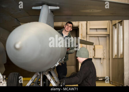 Le s.. Michael Albrecht et Senior Airman Colin Prutch du 52e Escadron de maintenance des aéronefs fixer une aile-monté réservoir au U.S. Air Force F-16CM Fighting Falcon à base aérienne de Spangdahlem, en Allemagne, Feb 6, 2018. Une tempête de neige, mettre un terme à l'exploitation des vols pour la journée mais ne s'arrête pas la nécessité pour l'entretien général de la flotte de Spangdahlem de F-16. Aviateurs, affecté à la 52e AMXS sont chargés avec le soin et l'entretien de l'aéronef américain uniquement à la suppression de l'spécialisés les défenses aériennes ennemies (SEAD) rôle dans le théâtre d'opérations européen. (U.S. Air Force Photo de 1er lieutenant Casey Banque D'Images