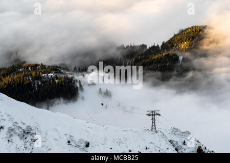 Le téléphérique de la montagne a fait son chemin à travers les nuages et passé la dernière capture arbres brumeux des jours lumière dorée. Banque D'Images