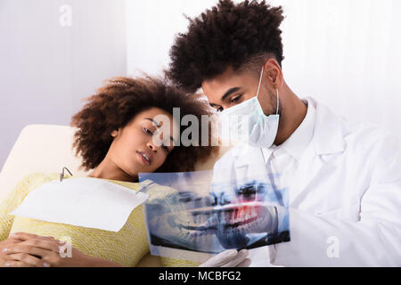 Male Dentist montrant les dents X-ray à Happy Female Patient In Clinic Banque D'Images