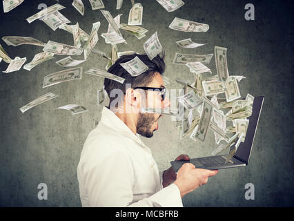 Side view of man holding laptop et gagner beaucoup d'argent dans les médias sociaux. Banque D'Images
