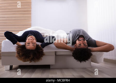 Happy Young Couple Lying On lit dans la chambre Banque D'Images