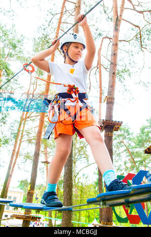 Jeune fille dans le faisceau de l'escalade et d'essayer dans un parc d'aventure. Banque D'Images