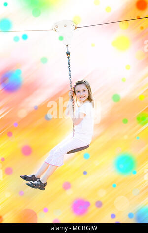 Peu gaie smiling girl faire de la tyrolienne dans la journée d'été. Avec l'arrière-plan flou flou coloré. Banque D'Images