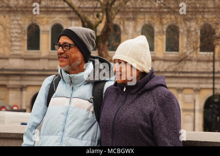 Un couple d'âge moyen pour une photographie sourire enveloppé dans des vêtements d'hiver à Trafalgar Square, Londres Banque D'Images