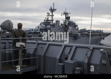 Corps des Marines des États-Unis Le Cpl. Maston, Victoria d'opérateur logistique avec l'élément de combat de la 13e unité expéditionnaire de Marines, montres le Wasp-classe d'assaut amphibie USS Essex recevoir le carburant de l'île de Whidbey-class amphibious landing ship dock USS Rushmore (LSD 47) lors d'un escadron amphibie et MEU Opération d'intégration (PMINT), le 30 mars 2018. PMINT est une évolution de la formation entre le groupe amphibie d'Essex et la 13e MEU, qui permet aux marins et soldats à s'entraîner comme une unité cohérente en vue de leur prochain déploiement. Banque D'Images