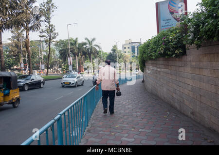 HYDERABAD, INDE - AVRIL 03,2018.Un piéton avec déjeuner fort dans la main marche sur un trottoir à côté de GVK Mall tôt le matin à Hyderabad, Inde Banque D'Images