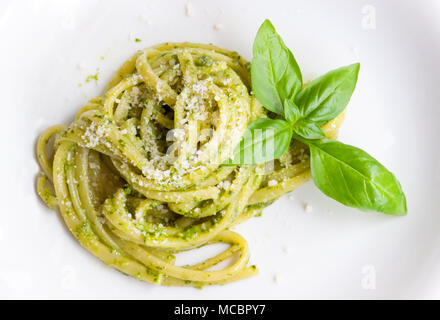 Les pâtes spaghetti avec sauce verte pesto original à Gênes (Genova) Italie sur plaque blanche fond, pâtes avec pesto de basilic herbes arrière-plan. Banque D'Images