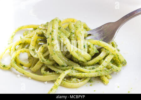 Les pâtes spaghetti avec sauce verte pesto original à Gênes (Genova) Italie sur plaque blanche fond, pâtes avec pesto de basilic herbes arrière-plan. Banque D'Images