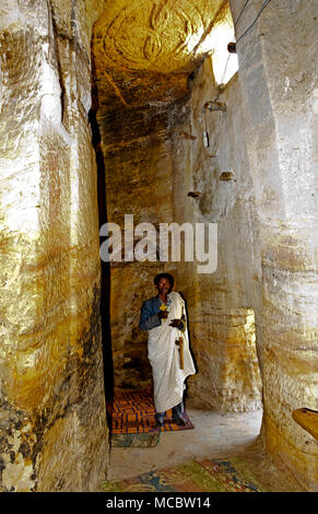 Prêtre orthodoxe, se tenant debout à l'intérieur d'un couloir de roche dans l'église rupestres Medhane Alem, région du Tigré, en Ethiopie Banque D'Images