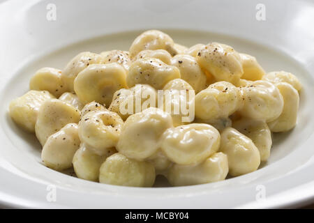 D'un coup frontal plat italien typique, un plaste de gnocchi à la crème de fromage gorgonzola et le poivre dans une plaque ronde blanche. Banque D'Images