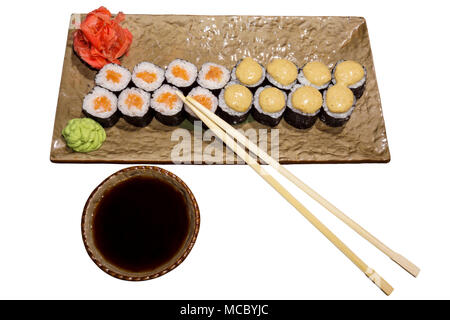 Deux types de rouleaux de sushi japonais traditionnels futomaki sur une plaque rectangulaire avec une sauce soja avec soucoupe et baguettes isolated on white zone Banque D'Images