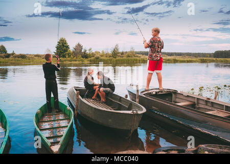 Dobrush, Bélarus - 25 juillet 2013 : Les Enfants du Bélarus de pêche en bois vieux bateaux à rame en été Coucher du Soleil Banque D'Images