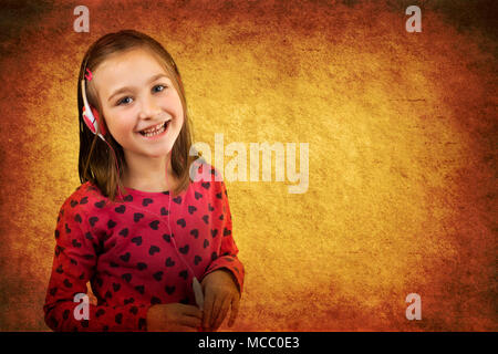 Petite fille heureuse avec un casque s'amusant à écouter la musique. Vintage grunge background. Banque D'Images