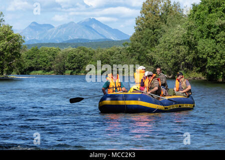 Rafting été sur le Kamchatka - groupe de touristes, voyageurs flottant sur un radeau sur la rivière calme sur fond de montagnes et de forêt verte Banque D'Images