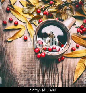 Tasse de thé de fines herbes aubépine rouge avec petits fruits et feuilles d'automne automne sur fond de bois rustique, vue du dessus. Banque D'Images