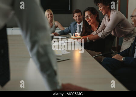 Collègues félicitant la collègue pour l'anniversaire et présentant le gâteau avec des bougies. les gens d'affaires célébrant l'anniversaire d'une collègue de travail dans c Banque D'Images