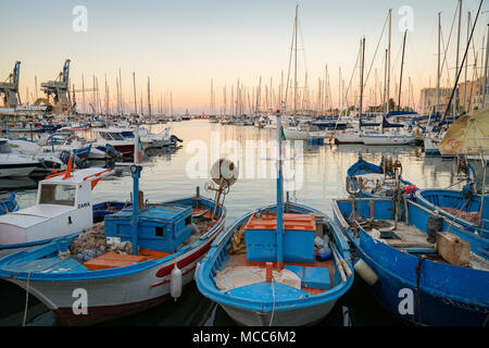 Vieux bateaux de pêche et de voiliers modernes dans l'ancien 'La Cala' port et marina à Palerme, Sicile, Italie, alors que le soleil se couche sur une journée d'été en août. Banque D'Images