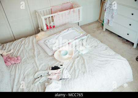 La chambre d'une mère est rempli de matériel pour bébé. Il y a un matelas à langer et des vêtements s'étala sur le lit. Banque D'Images