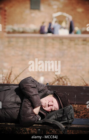 Pologne Varsovie un rough sleeper sans-abri dort sur un banc à côté de la vieille ville de mur de la ville Banque D'Images