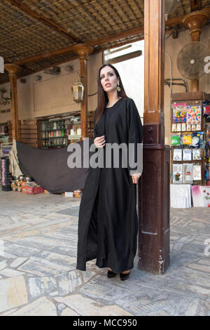 Femme vêtue de abaya debout dans le vieux marché. Banque D'Images