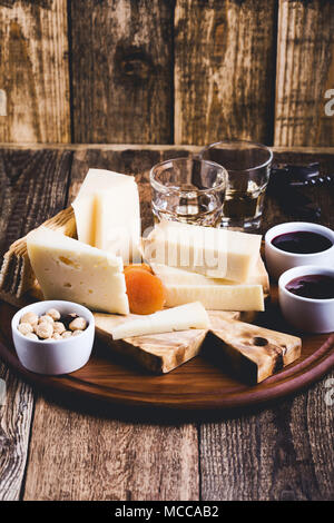 Assiette de fromages, confiture de fruits, de noix et de vin sur planche à découper en bois, de délicieux amuse-bouche Banque D'Images