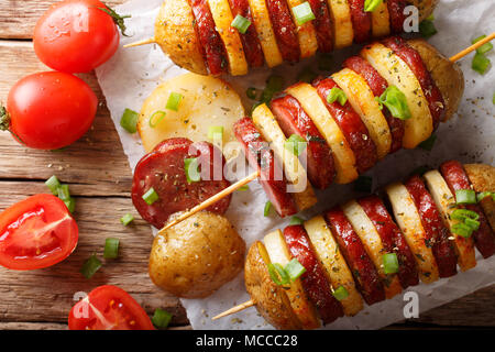 Grillades barbecue Brochettes de pommes de terre chaudes avec salami saucisses et l'oignon vert gros plan sur la table. Haut horizontale Vue de dessus Banque D'Images