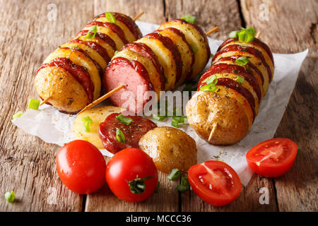 Chachlyk fraîchement préparés à partir de brochettes de pommes de terre avec de la saucisse et le salami tomates, oignons verts close-up sur la table horizontale. Banque D'Images