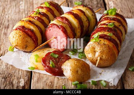 Barbecue brochettes de pommes de terre avec de la saucisse et le salami oignon vert close-up sur la table horizontale. Banque D'Images