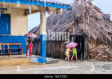 Guna Yala, Panama - mars 2018 : Groupe de jeunes enfants avec parapluie en pluie sur rue dans un village kuna, îles San Blas Banque D'Images