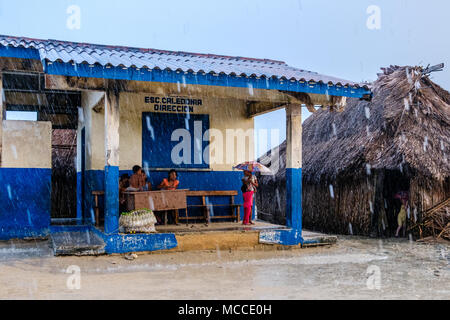 Guna Yala, Panama - mars 2018 : Groupe de jeunes enfants avec parapluie en pluie sur rue dans un village kuna Banque D'Images