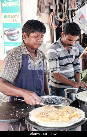 Faire cuire le Masala Dosa sur une plaque chaude en plein air dans un marché de Mumbai Banque D'Images