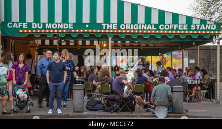 Cafe du monde, La Nouvelle-Orléans, Louisiane, États-Unis. Une foule de gens devant le célèbre café à côté d'une fanfare, lumière dorée sur auvent. Banque D'Images