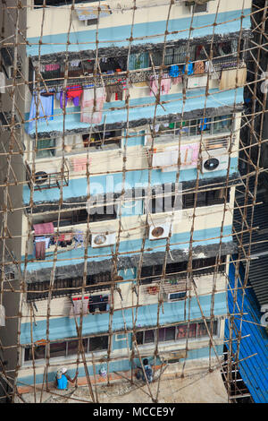 Les constructeurs de la réparation d'un bâtiment en utilisant des échafaudages en bois traditionnelle indienne en bois poteaux attachés ensemble avec de la corde, Malabar, Mumbai, Inde Banque D'Images