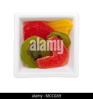 Morceaux de fruits confits dans un bol carré isolé sur fond blanc Banque D'Images