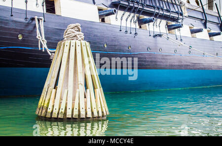 Bollard en bois dans l'eau avec des cordes attachées au navire de guerre USS Constellation historique dans le port intérieur de Baltimore USA Banque D'Images