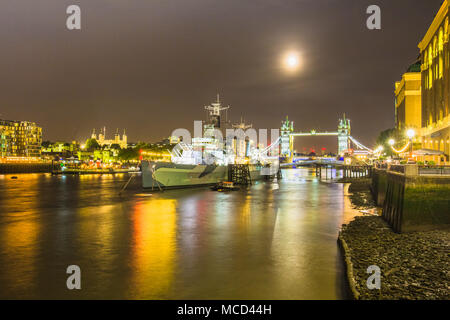 Le HMS Belfast, la Tamise, le Tower Bridge et la Tour de Londres vue de l'hôtel de ville de nuit de South Bank, Londres, Angleterre Royaume-uni avec des réflexions Banque D'Images