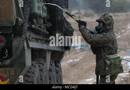 Un soldat polonais avec le 1er Bataillon, 15e Brigade mécanisée, procède à un lavage pour décontaminer un Stryker américain au cours de produit chimique, biologique, radiologique et nucléaire (CBRN) formation à une gamme près de la zone d'entraînement Bemowo Piskie, Pologne, 16 février 2018. Ce soldat est une partie de l'unique groupe de combat multinationales, composé de États-Unis, Royaume-Uni, croate et soldats roumains qui servent avec la 15e Brigade mécanisée polonaise comme une force de dissuasion dans le nord-est de la Pologne à l'appui de l'OTAN vers l'amélioration de la présence. (U.S. Photo de l'armée par la CPS. Andrew McNeil/ Mobile 22e Détachement des affaires publiques) Banque D'Images