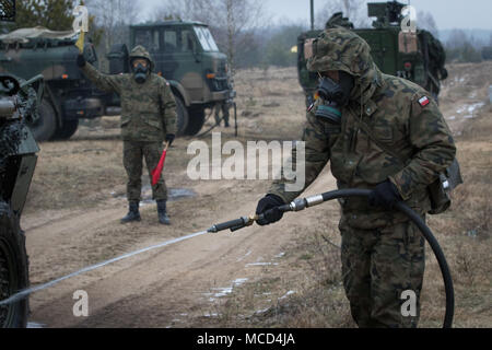Un soldat polonais avec le 1er Bataillon, 15e Brigade mécanisée, procède à un lavage pour décontaminer un Stryker américain tout en menant à une formation de contamination près de la gamme Bemowo Piskie Domaine de formation, Pologne, 16 février 2018. Ces soldats sont une partie de l'unique groupe de combat multinationales, composé de États-Unis, Royaume-Uni, croate et soldats roumains qui servent avec la 15e Brigade mécanisée polonaise comme une force de dissuasion dans le nord-est de la Pologne à l'appui de l'OTAN vers l'amélioration de la présence. (U.S. Photo de l'armée par la CPS. Andrew McNeil/ Mobile 22e Détachement des affaires publiques) Banque D'Images