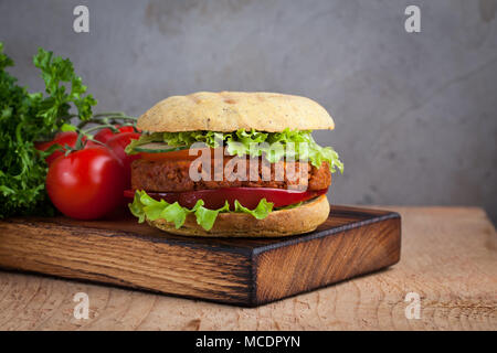 Fresh Burger végétalien avec tomates, concombres, laitue et végétalien escalope sur planche de bois. Banque D'Images