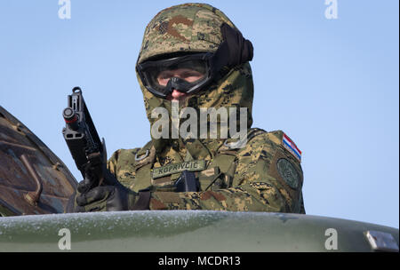 Un soldat de l'artillerie croate affecté à la batterie tire comme sécurité volcan il monte dans le poste du tireur de son équipe's rocket système d'artillerie véhicule lors d'un exercice de préparation tout en participant à l'exercice de groupe de combat Pologne à Puma une gamme près de la zone d'entraînement Bemowo Piskie, Pologne, le 22 février 2018. Ce soldat est une partie de l'unique groupe de combat multinationales, composé de États-Unis, Royaume-Uni, croate et soldats roumains qui servent avec la 15e Brigade mécanisée polonaise comme une force de dissuasion dans le nord-est de la Pologne à l'appui de l'OTAN vers l'amélioration de la présence. (U.S. Photo de l'armée par la CPS. Et Banque D'Images