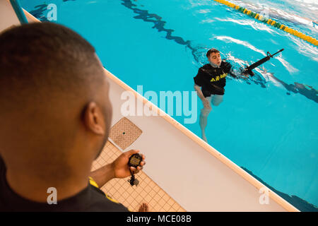 Un soldat américain fois Sgt. Jacobus de bois, avec la Police militaire de Bruxelles à la U.S. Army Garrison Benelux, qu'il nage tout en gardant la plupart de ses armes hors de l'eau au cours de la garnison's Best Warrior la concurrence dans la piscine du Grand Quartier général des Puissances alliées en Europe, Belgique, le 21 février 2018. (U.S. Photo de l'armée par Visual Spécialiste de l'information, Pierre-Etienne Courtejoie) Banque D'Images