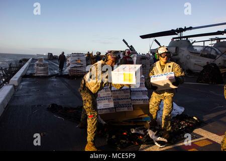 L'USS New York (LPD 21) est un quai de transport amphibie de classe San Antonio de la marine américaine mis en service en 2009. Le 25 février 2018, les Marines affectés à la 26e unité expéditionnaire des Marines distribuent des fournitures lors d'un réapprovisionnement en mer alors qu'ils sont déployés dans la zone d'opérations de la 6e flotte américaine en mer Méditerranée. L'image d'archive enregistre la logistique à bord et l'activité de préparation. Banque D'Images